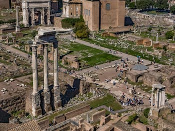 The three columns of the Castor and Pollux Temple with, on the right, with its half circular plate roof, the Jules Cesar Temple in the Roman Forum in Italy